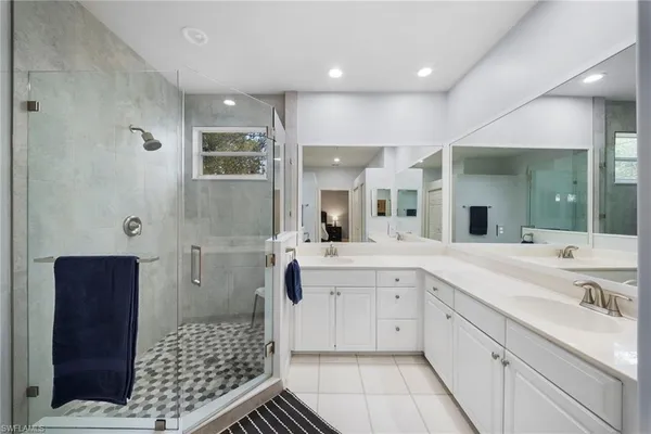 a spacious bathroom with a double vanity sink a mirror and a shower