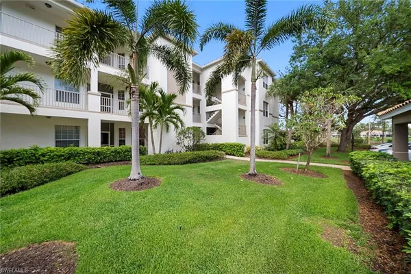 a view of a white house with a yard and palm trees