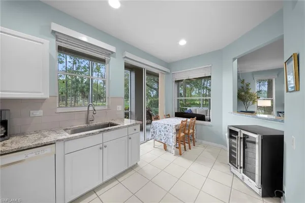a large white kitchen with granite countertop a stove a sink a dining table and chairs
