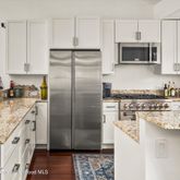 a kitchen with stainless steel appliances granite countertop a refrigerator a stove and a sink