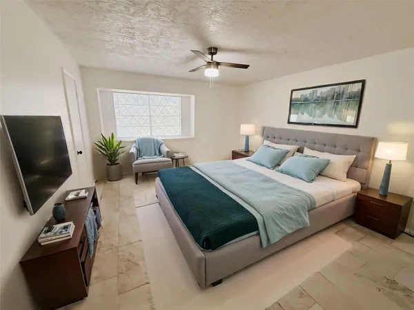 a bedroom with a bed a couch and a flat screen tv