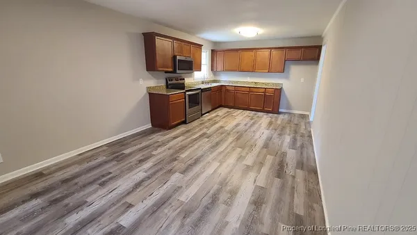 a kitchen with granite countertop a sink cabinets and stainless steel appliances