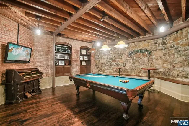 a room with furniture pool table wooden floor and a flat screen tv