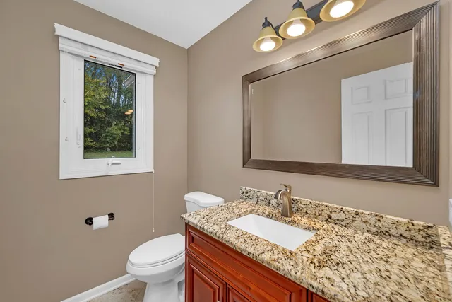 a bathroom with a granite countertop toilet a sink and a mirror