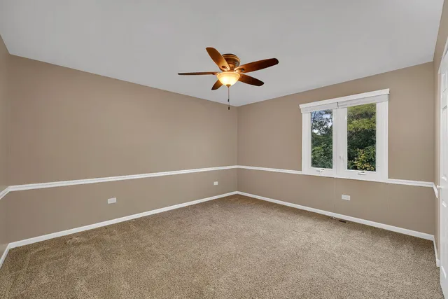 an empty room with a window and a ceiling fan