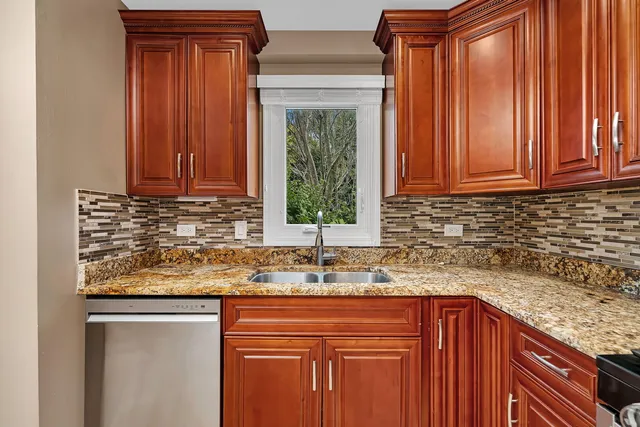 a kitchen with granite countertop wooden cabinets a sink and dishwasher