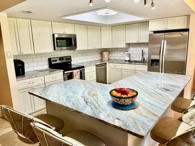 a kitchen with stainless steel appliances granite countertop a sink a stove and a refrigerator