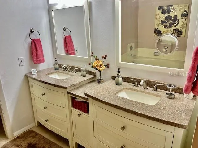 a bathroom with a granite countertop double vanity sink mirror and