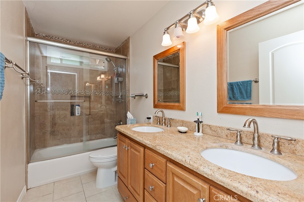 1834 West Las Palmas Circle Orange, CA 92868 - Photo 18 of 25 a bathroom with a granite countertop sink a toilet a mirror and shower