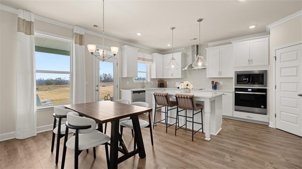 1787 Goodwin Drive Hampton, GA 30228 - Photo 20 of 55 a kitchen with stainless steel appliances kitchen island granite countertop a dining table chairs and white cabinets