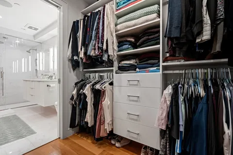 a view of walk in closet with clothes and shoes