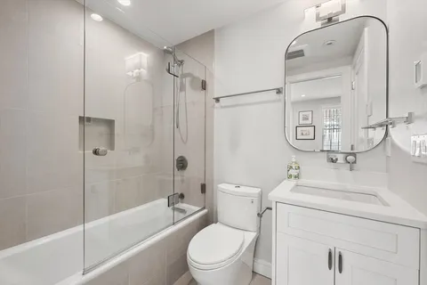 a bathroom with a bathtub shower sink mirror vanity and toilet