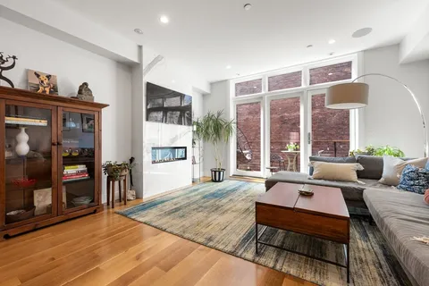 a living room with furniture large window and wooden floor