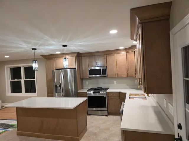 a kitchen with kitchen island counter top space a sink stainless steel appliances and windows
