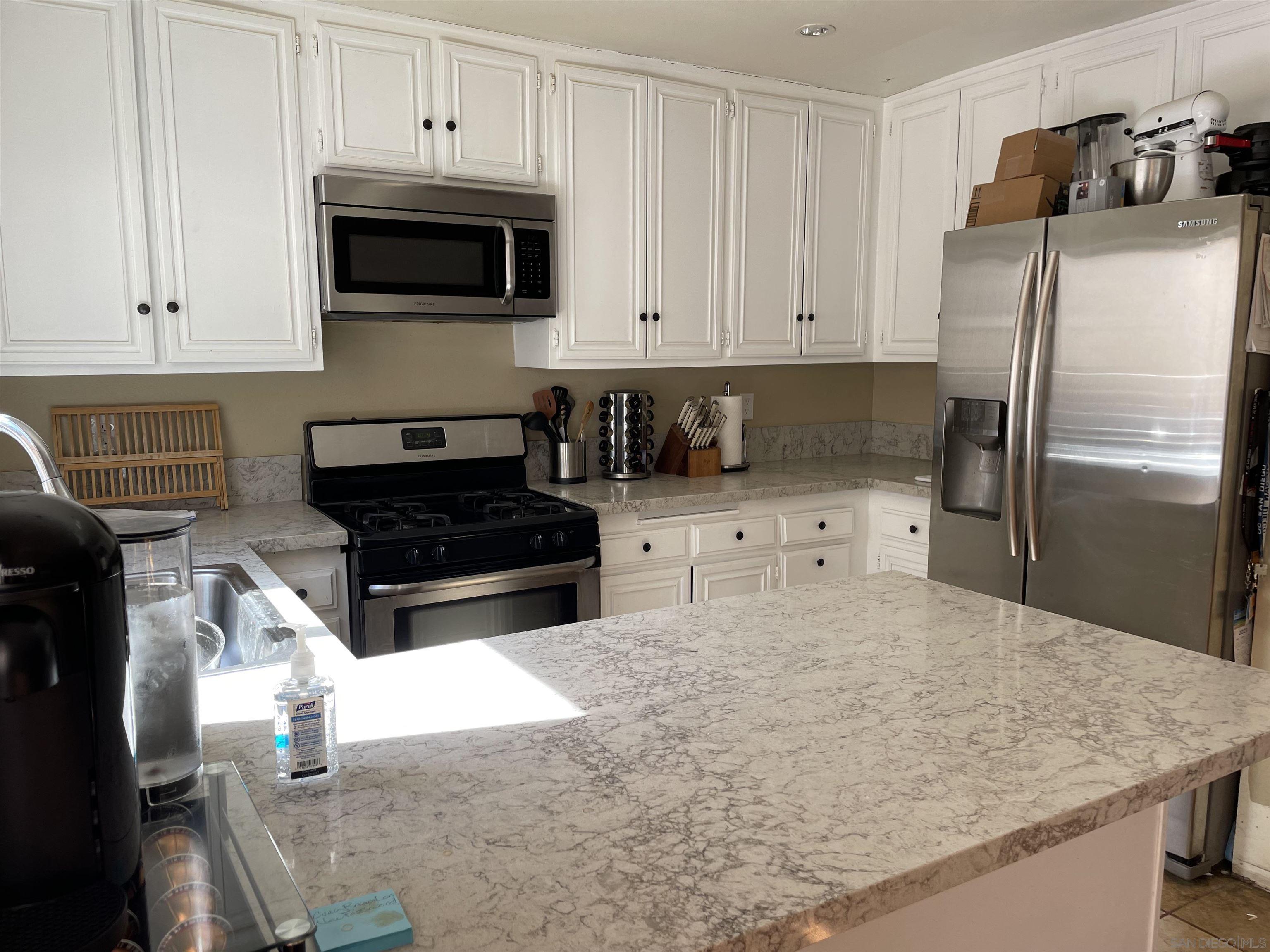 a kitchen with granite countertop a refrigerator a stove a microwave and cabinets