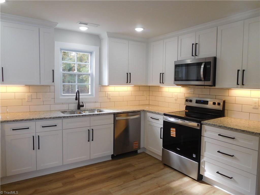 3830 Robinhood Road Winston-Salem, NC 27106 - Photo 11 of 30 SHAKER CABINETS, TILE BACKSPLASH, GRANITE COUNTERS, SS APPLIANCES REMAIN & UNDER CABINET LIGHTS ARE A FEW FEATURES OF THIS KITCHEN.