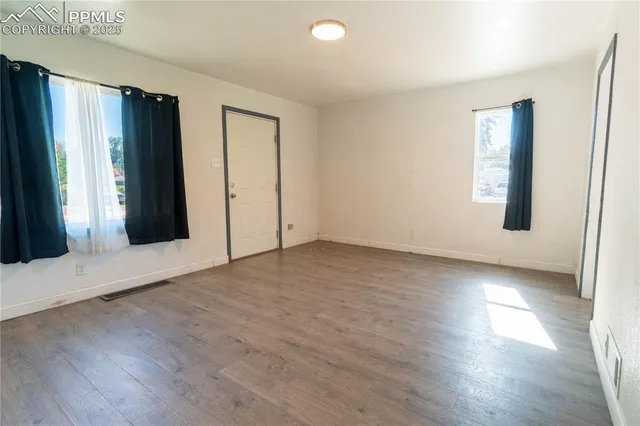 an empty room with wooden floor and windows