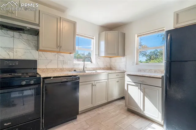 a kitchen with white cabinets appliances and a window