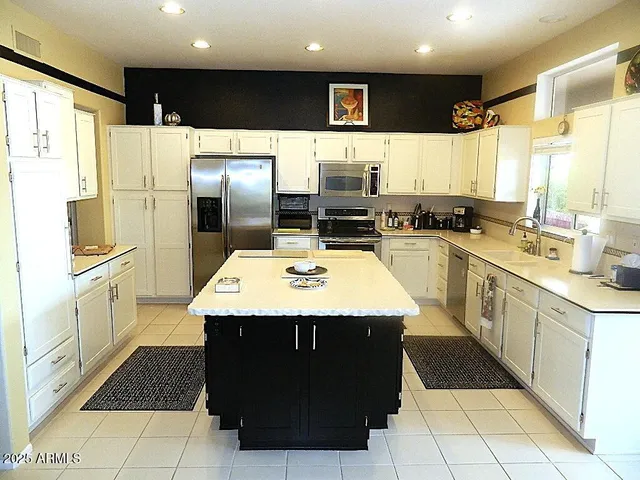 a kitchen with stainless steel appliances kitchen island granite countertop a refrigerator a sink dishwasher and a stove