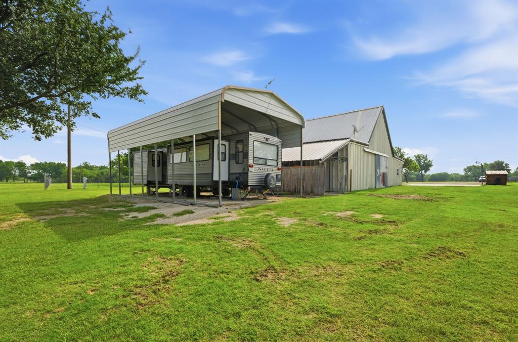 465 Emberson Ranch Road Pilot Point, TX 76258 - Photo 29 of 37 Expansive green space featuring a metal carport structure, a large barn with a metal roof, and a small outbuilding