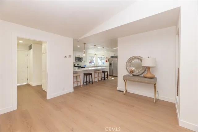 a kitchen with stainless steel appliances kitchen island granite countertop a table chairs refrigerator and microwave