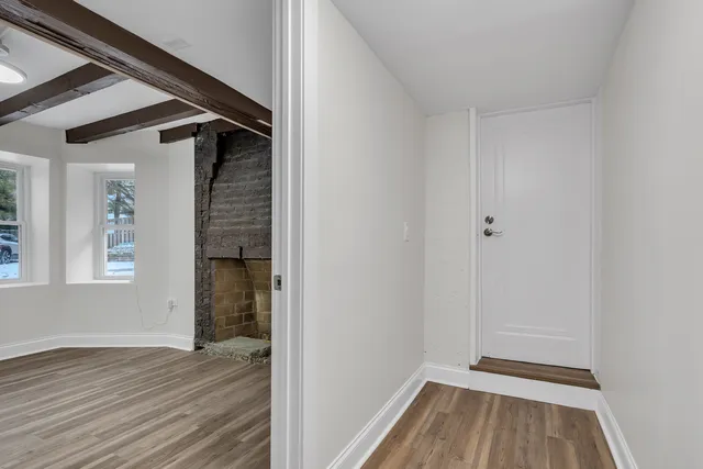 a view of a hallway with wooden floor and a window