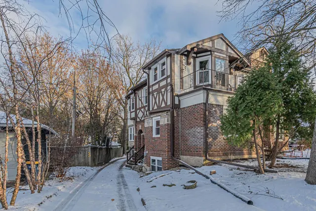 a view of a brick house with large windows and wooden fence