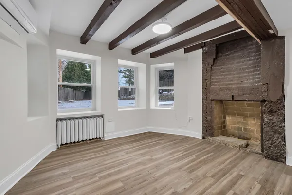an empty room with windows and fireplace