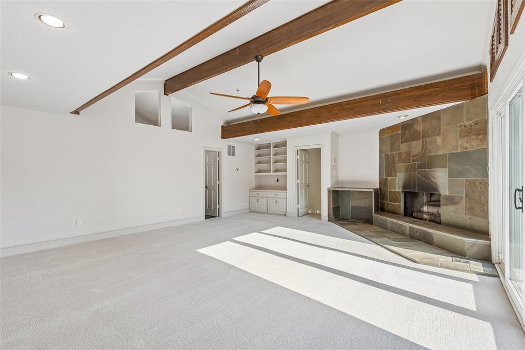 1155 Point Vista Road Hickory Creek, TX 75065 - Photo 34 of 40 Spacious room featuring exposed ceiling beams, a stone-clad fireplace, integrated shelving, and carpet flooring