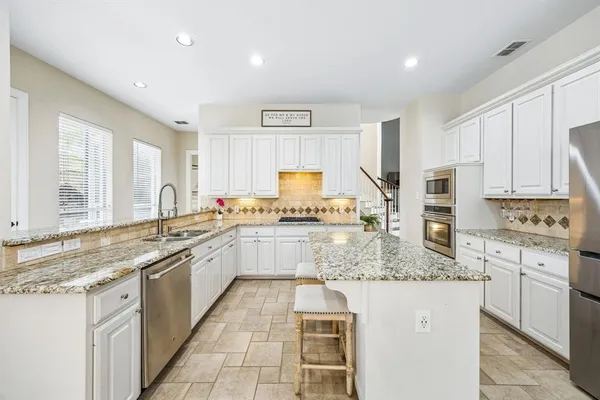 a kitchen with stainless steel appliances granite countertop a stove sink and cabinets