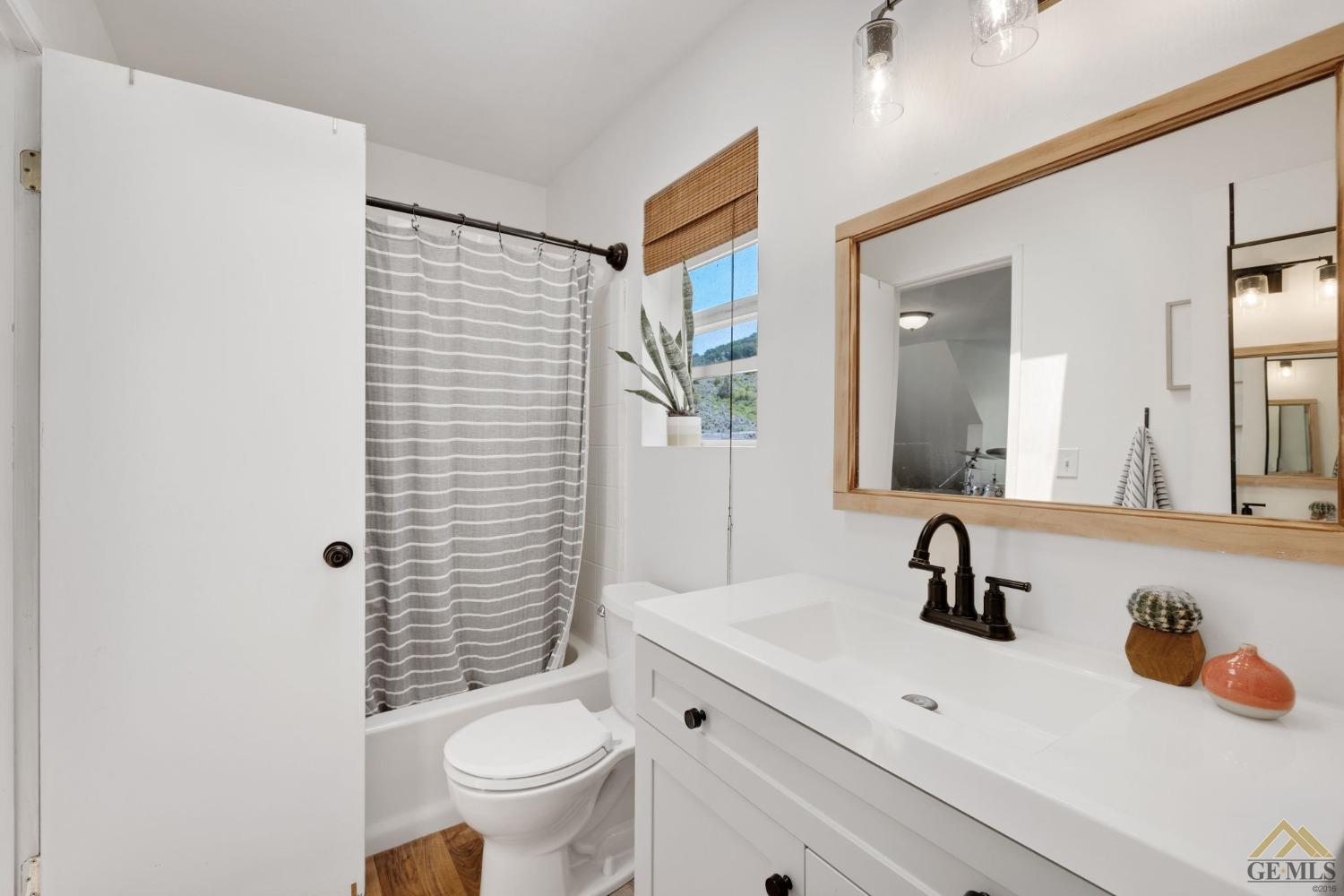 Undisclosed Address Tehachapi, CA 93561 - Photo 33 of 57 a bathroom with a sink a toilet a mirror and shower curtain