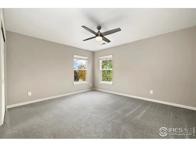 an empty room with windows and ceiling fan