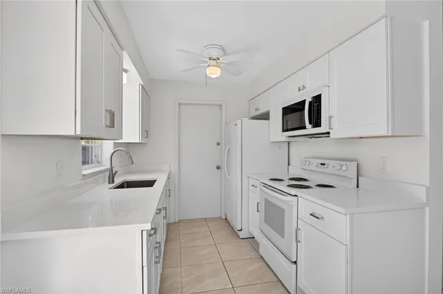 a kitchen with stainless steel appliances a white stove top oven a sink dishwasher and a refrigerator with wooden cabinets