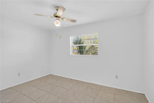 an empty room with wooden floor and ceiling fan