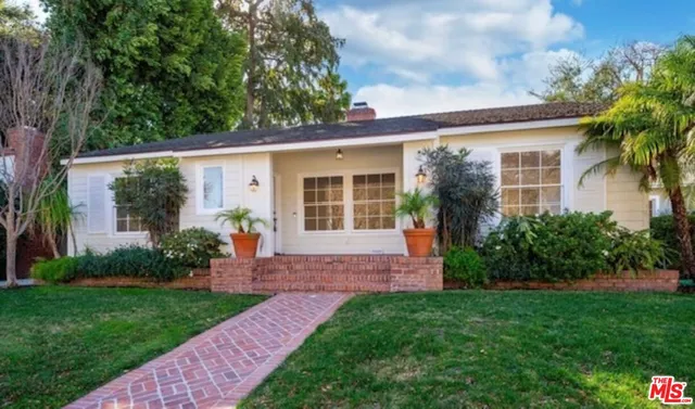 a view of a yard in front of a house with plants and large tree