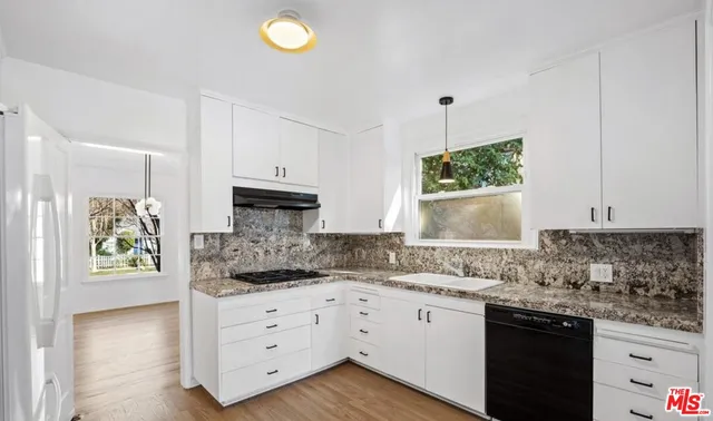 a kitchen with granite countertop a stove a sink and a microwave