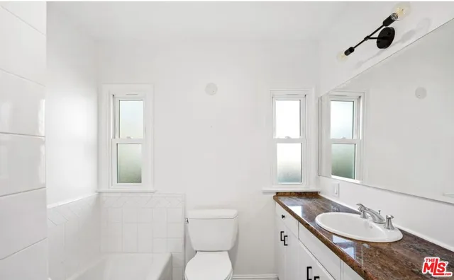 a bathroom with a granite countertop sink toilet a mirror and shower