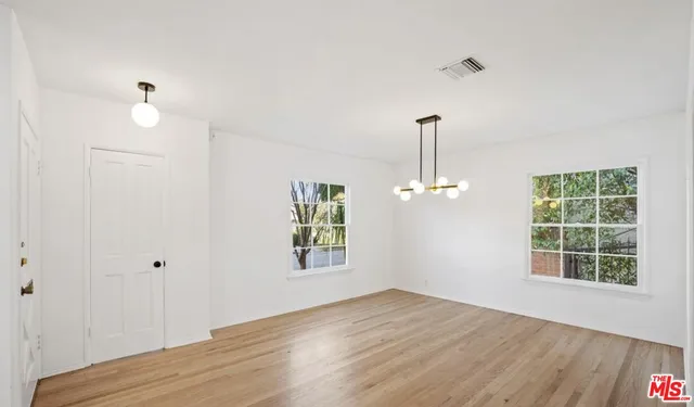 a view of empty room with wooden floor and window