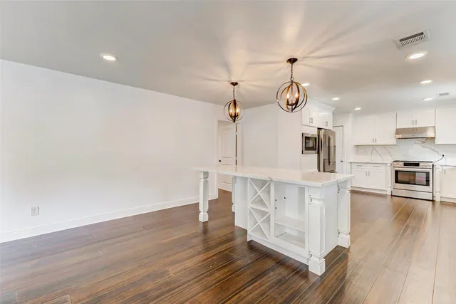 a large kitchen with lot of wooden floor and stainless steel appliances