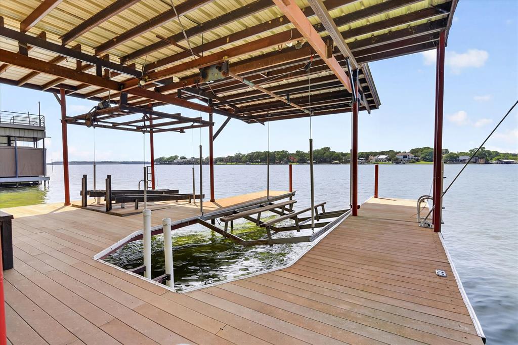 8877 Random Road Fort Worth, TX 76179 - Photo 31 of 40 Covered boat dock featuring composite decking, metal roofing, a boat lift, and a swim ladder
