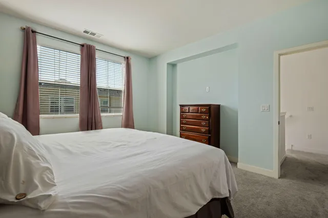 a bedroom with a bed a dresser and a window