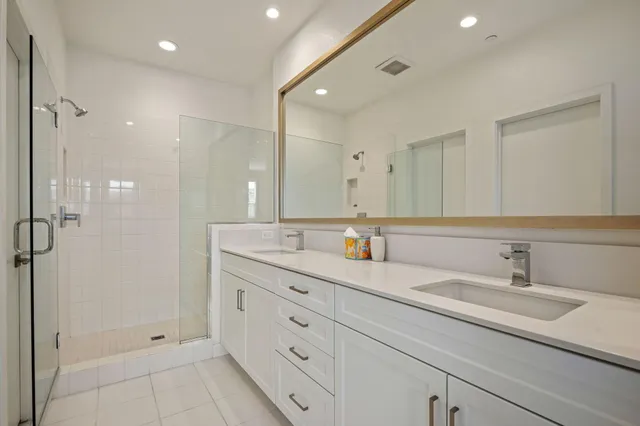 a bathroom with a double vanity sink mirror and shower