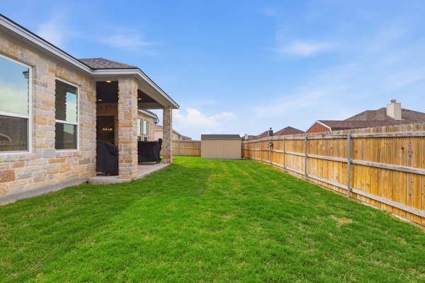 133 Greg Lane Jarrell, TX 76537 - Photo 22 of 24 Spacious backyard featuring a covered patio, stone exterior, and wood privacy fencing