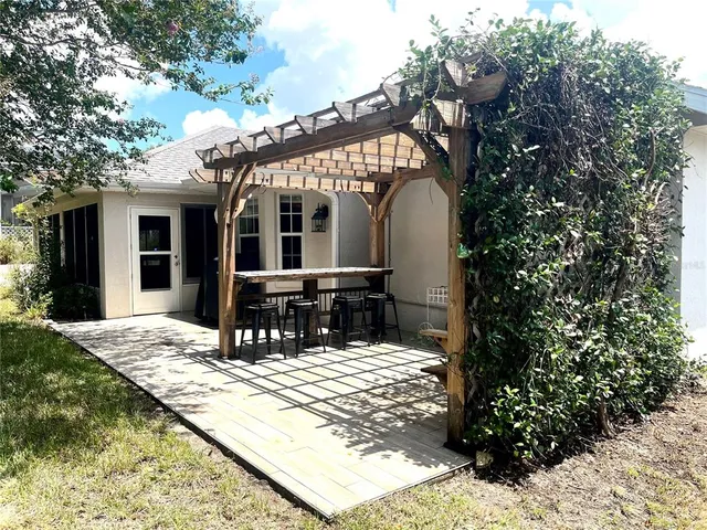 a view of a house with a wooden bench next to a yard