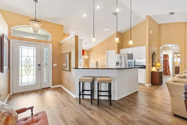 a open kitchen with stainless steel appliances granite countertop a kitchen island a stove a refrigerator a sink a dining table and chairs with wooden floor