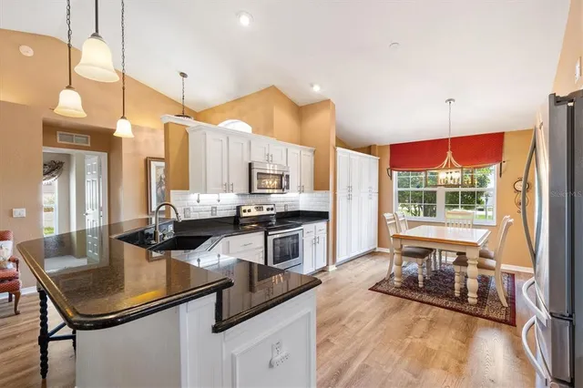 a kitchen with stainless steel appliances a sink a counter top space a large window and cabinets