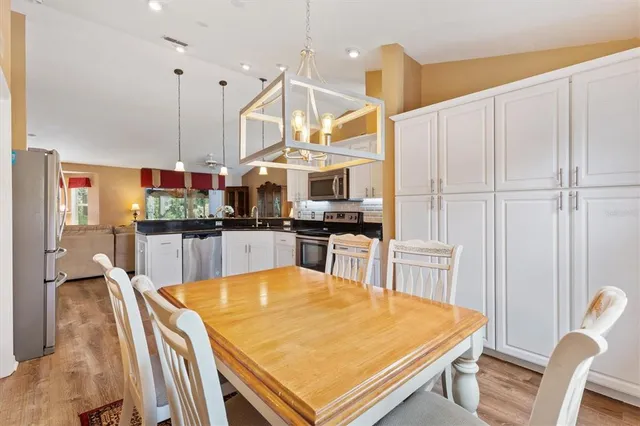 a kitchen with stainless steel appliances kitchen island granite countertop a table chairs and a refrigerator