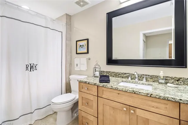 a bathroom with a granite countertop sink mirror vanity and toilet