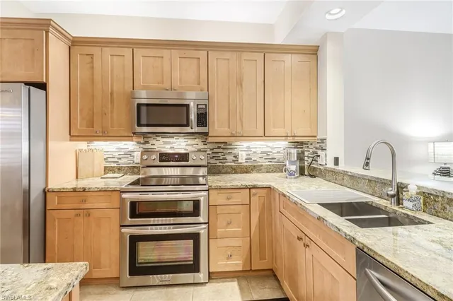 a kitchen with granite countertop white cabinets sink and stainless steel appliances
