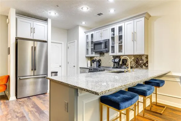 a kitchen with stainless steel appliances granite countertop a refrigerator a sink and a stove